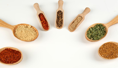 Different spices and herbs in wooden spoons isolated on white