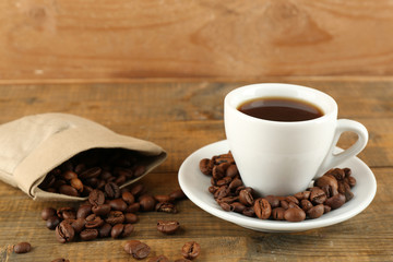 Cup of coffee with beans on rustic wooden background