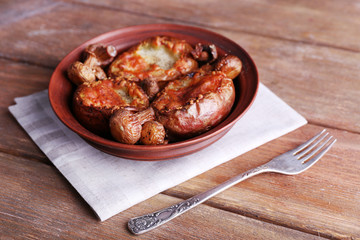 Baked potatoes with mushrooms in bowl on wooden table