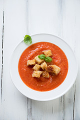 Gazpacho with croutons on a white wooden surface, above view
