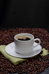 Coffee cup and saucer and coffee beans. Dark background.