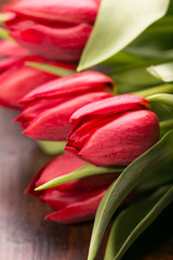 Naklejka premium Red tulips on an antique wooden background