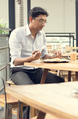 Asian Indian business man reading newspaper while drinking a cup