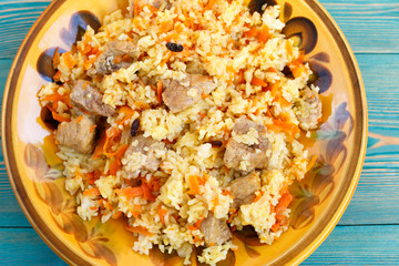 oriental pilaf, rice with meat and carrot on yellow plate