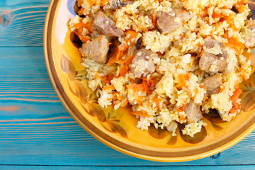 pilau from rice, meat, carrot and barberry in yellow plate