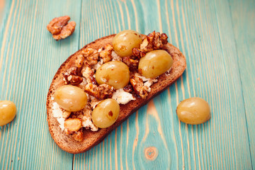 rye toast with ricotta, grape and walnut on blue table