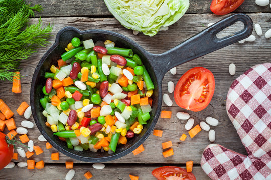 Mixed vegetables in vintage frying pan, pot holder and ingredien