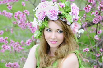 Fototapeta premium Beautiful girl in a flowered garden peach