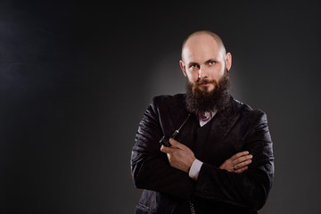 Bald bearded man holding a pipe in crossed hands.