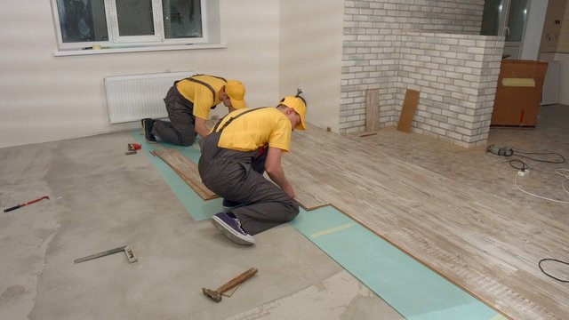 Team of builders make renovation of apartment. Laying parquet.