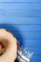 Mexican background with sombrero and traditional serape rug or blanket on old blue wood planked...