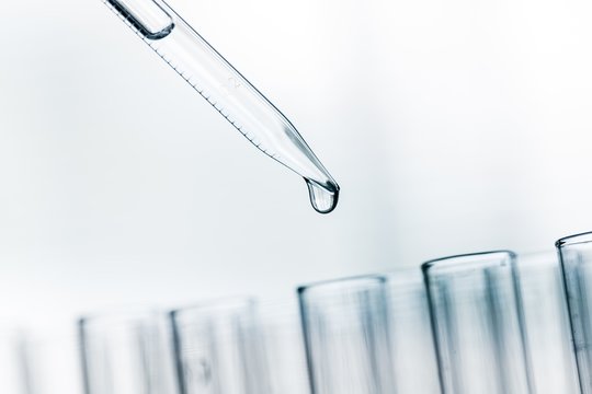 Lab. A close-up of a laboratory glass pipette with emerging drop