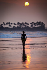 Fototapeta premium Woman walking on beach at sunset