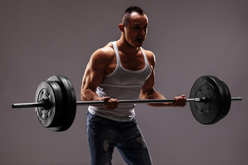 Fototapeta na wymiar Strong muscular man lifting a heavy barbell