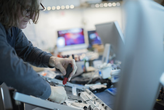 A m an using a screwdriver on the circuit boards of a computer. Repair technician.
