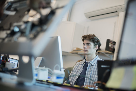 A man seated at a computer, in a repair shop. 