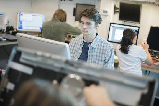 A man seated at a computer, in a repair shop. 