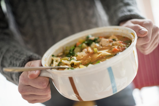 Close up view of a man holding a bowl with a vegetable stew.