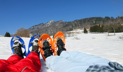 couple with blue and orange snowshoes in the mountains