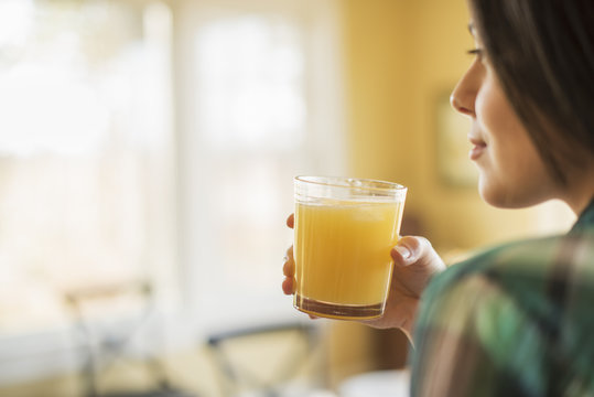 A woman holding a glass of orange juice.