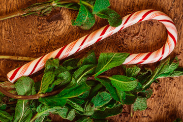 Candy canes with mint leaves  on a wooden background
