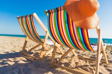 Deck. two deckchairs on a pebbled beach, facing out to sea