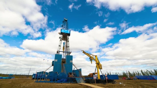 Timelapse shot of Blue Drilling rig on the background of moving clouds