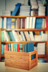 Books in wooden crate on bookshelves background