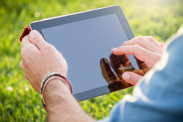 Adult man using a digital tablet at the park - obrazy, fototapety, plakaty