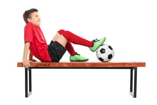 Pensive junior football player sitting on a bench