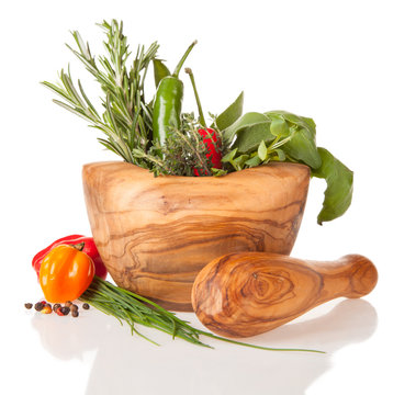 Wooden mortar with herbs on white background