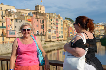 Two women on background of colorful houses in Girona, Spain.