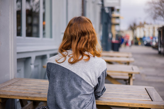 Young woman sitting on bench outside pub
