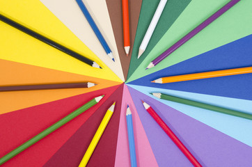 Color pencils on rainbow colors paper background.