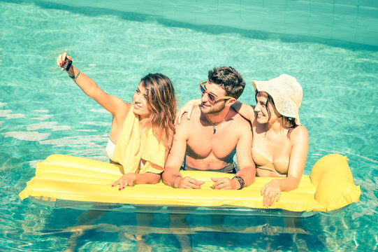 Best friends taking selfie at swimming pool with yellow airbed