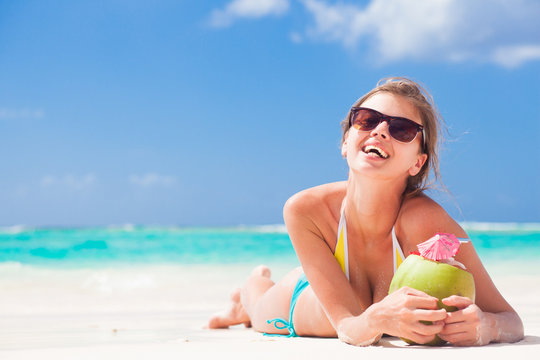 woman in bikini with fresh coconut juice on tropical beach