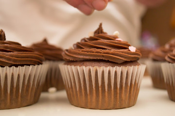 Chocolate cupcake getting sprinkles