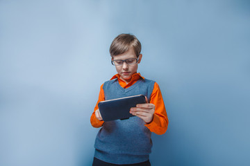 European-looking boy of ten years in glasses holding tablet in