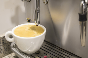 Pouring a coffee espresso on a machine in a white mug