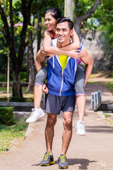 Asian man carrying his girlfriend piggyback for sport