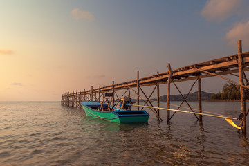 Sunset over the beautiful tropical beach with bridge and boat