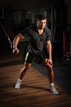 Young man doing one arm standing high cable fly