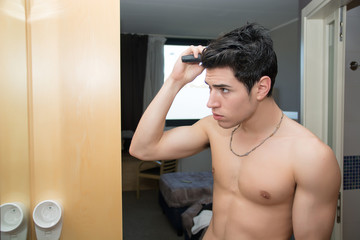 Young Man Brushing Hair in Mirror Getting Ready to Go Out