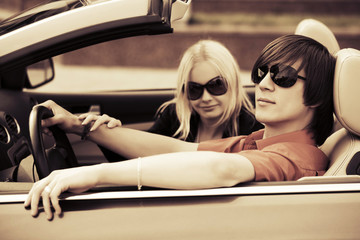 Happy young couple driving convertible car