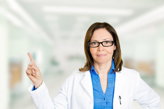 Confident female doctor with glasses pointing away with finger