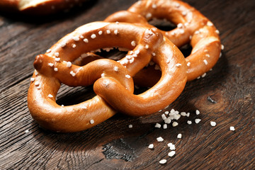 Fresh pretzels with sea salt close-up on  dark board background - obrazy, fototapety, plakaty