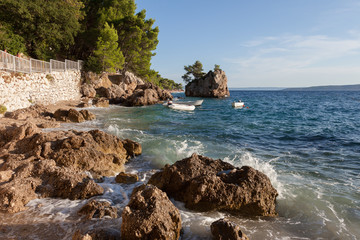 Coast of Croatia. Rocks, boats and pine trees.