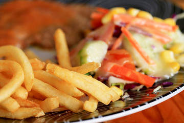 Steaks, pork, french fries with salad.