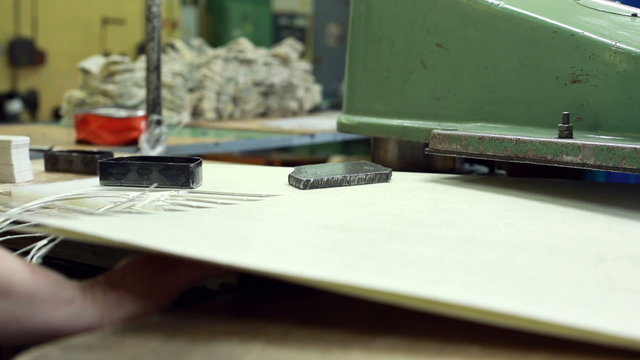 Worker cuts parts using semi-automatic machine