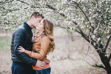 Young beautiful couple in a blooming garden. Spring mood